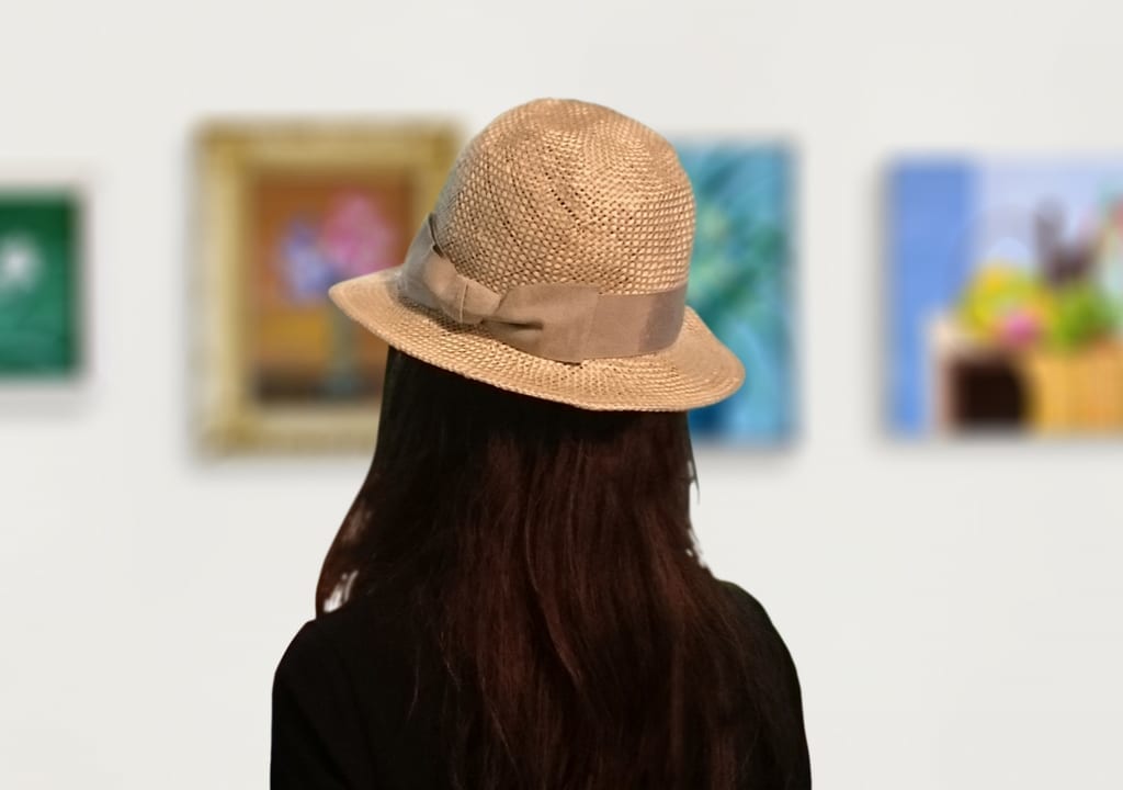 絵画を見る帽子をかぶった女性