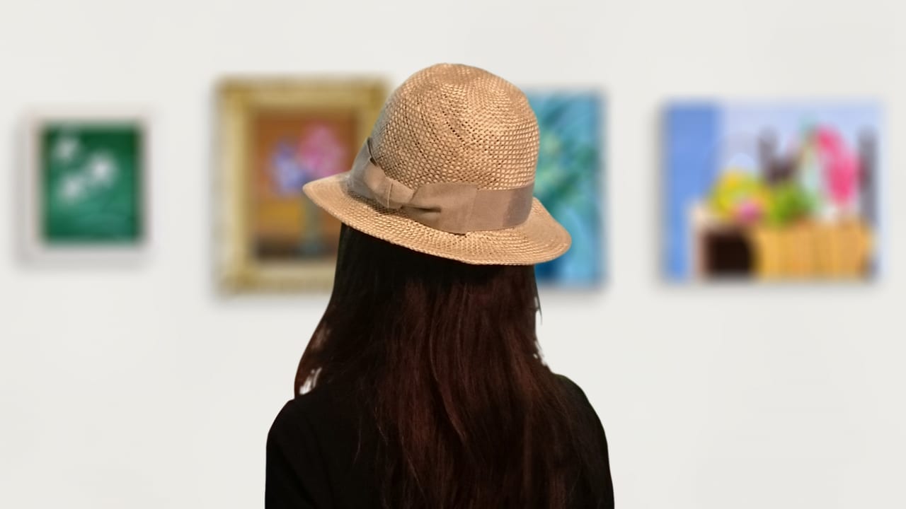 絵画を見る帽子をかぶった女性